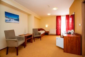日利纳波什酒店的酒店客房,配有一张床、一张桌子和椅子