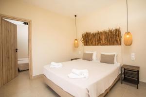 法里拉基Atma Beach Rooms & Suites的卧室配有白色的床和2条毛巾