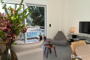 比雷埃夫斯La Mer Apartment by LobbySquare的客厅配有沙发和鲜花桌