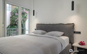 比雷埃夫斯La Mer Apartment by LobbySquare的白色的卧室设有床和窗户