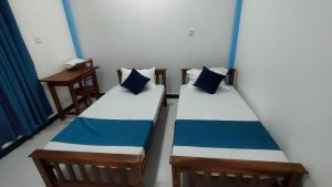 马纳尔Victory's Gardens的蓝色和白色的客房内的两张床