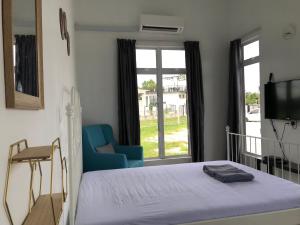 巴西富地Rumah Sawah Homestay Pasir Puteh的卧室配有床、椅子和窗户。