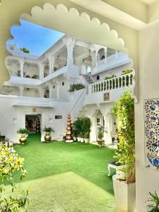 乌代浦杰加特尼瓦斯宫殿酒店的一座白色的大建筑,有绿色的院子