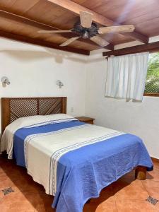 特隆戈内斯Casita Monarca的一间卧室配有一张带吊扇的床