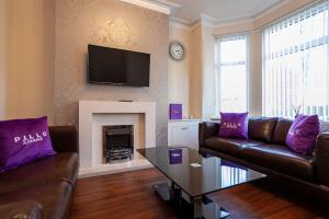 曼彻斯特Pillo Rooms - Spacious Cosy 2 Bedroom House by Bridgewater Canal的客厅配有沙发和带紫色枕头的壁炉