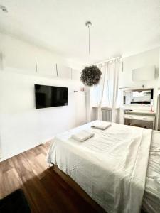 塞格拉泰white home near Linate的白色卧室配有床和平面电视