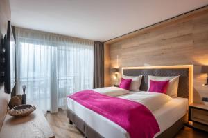 瓦格赖恩Hotel Adapura Wagrain的一间卧室配有一张带粉色毯子的大床