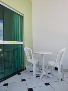 普拉杜POUSADA PRAIAMAR的客房内的2把白色椅子和1张桌子