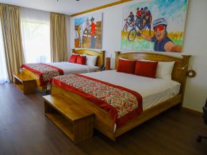 利比里亚瓜齐佩林庄园火山牧场农场酒店及温泉的酒店客房设有两张床,墙上挂有绘画作品