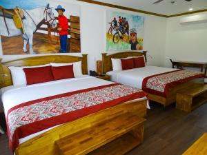利比里亚瓜齐佩林庄园火山牧场农场酒店及温泉的一间卧室设有两张床,墙上挂着一幅画