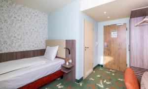 塞恩德Hotel & Restaurant Hubertus Sehnde的小房间设有一张床和一把椅子