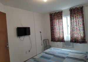 巴拉奈里奥-坎布里乌Residencial Louise的卧室配有一张床,墙上配有电视
