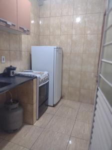 瓜拉廷格塔Kitnet completa的厨房配有白色冰箱和炉灶。