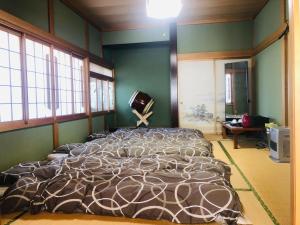 八户市青森伝統芸能を楽しめる繭子の宿的一张大床,位于带绿色墙壁和窗户的房间