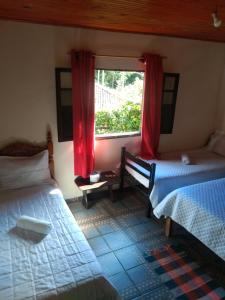 利马杜阿蒂Du vadinho hotel的一间卧室设有两张床,窗户配有红色窗帘