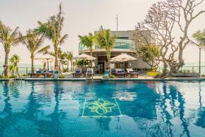 绥和市Sala Grand TuyHoa Hotel的一座带椅子和棕榈树的游泳池以及一座建筑