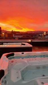 那不勒斯甜梦住宿加早餐旅馆的一座享有日落美景的建筑屋顶上的热水浴池