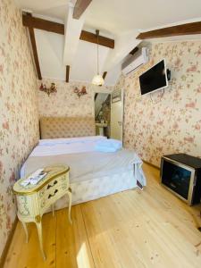 姆茨赫塔Tatin - Hotel & Café in Mtskheta的一间卧室配有一张带桌子的床和一台电视。