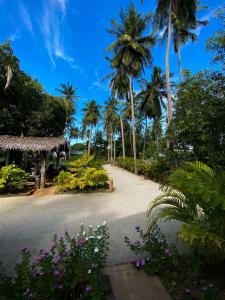 亭可马里Elena Garden Resort and Restaurant的棕榈树和鲜花在房子前面的道路