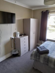 Immingham黑牛旅馆的一间卧室配有一张床、梳妆台和电视。
