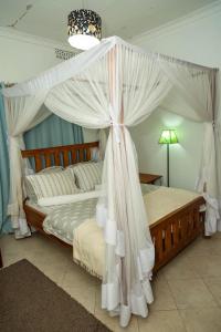 阿鲁沙Blue elephant villas的卧室配有带白色窗帘的天蓬床
