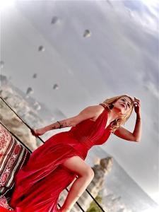 格雷梅Sevin Stone Hotel的站在栏杆上的穿着红色衣服的女人