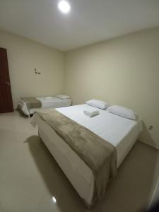 穆库热Hospedaria São João的一间卧室配有一张白色大床和两张单人床。