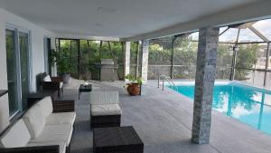 珊瑚角Cape Coral Mini Palace的一座带白色家具的游泳池的房子
