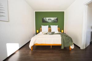 吕贝克HejU - Luxury Aussicht - Kingsize Bed - Kitchen - Bathtub的一间卧室配有一张带绿色墙壁的床