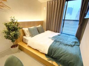 大阪R Hotel Namba的一间卧室,配有一张带植物和窗户的床
