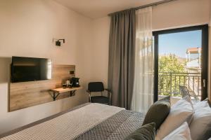 斯卡拉斯卡拉旅馆的一间卧室设有一张床、一台电视和一个阳台。