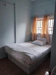 马迪凯里Kamadhenu Residency Homestay Hotel Coorg Madikeri的一张大床,位于带两个窗户的房间