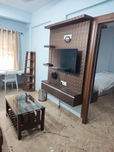 马迪凯里Kamadhenu Residency Homestay Apartment Coorg Madikeri的一间客厅,客厅的砖墙内配有电视