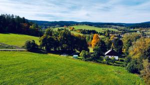 ZdíkovChalupa Zdíkov na Šumavě的一片绿地,树木林立,远处有村庄