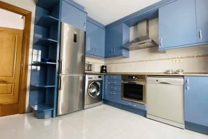 利亚内斯apartamentos lleguera 1的厨房配有蓝色橱柜和不锈钢冰箱