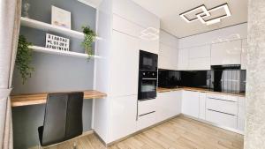 布达佩斯Diamond Luxury Apartment的厨房配有白色橱柜和黑椅