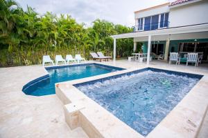 ParaísoVilla impecable con piscina privada en Juan Dolio的一个带椅子的游泳池以及一座房子