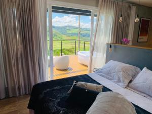 本图贡萨尔维斯Vista Vigneti Albergo & Vino - Vale dos Vinhedos的一间卧室配有一张床和一个配有浴缸的阳台