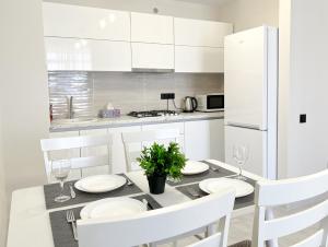 基希讷乌OASIS, Charming 1BD apartment with living room的白色的厨房配有餐桌和白色橱柜。