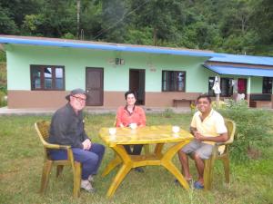 GorkhāGorkha Organic Agro Farm的三人坐在房子前面的桌子上