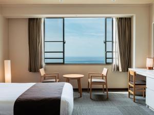 淡路KAMENOI HOTEL Awajishima的配有一张床、一张书桌和一扇窗户的酒店客房