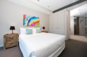 堪培拉堪培拉欧若拉公寓的卧室配有一张白色大床和淋浴