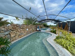 LaSersita Casitas and Water Spa Beach Resort by Cocotel的一个带石墙和遮阳伞的游泳池