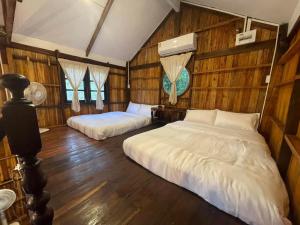 Ban Don KlangBaanraipoonwana Baanboonmak的木墙客房的两张床