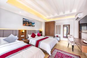 加德满都Hotel Ama-La, Thamel, Kathmandu的酒店客房设有两张床、一张桌子和一张书桌。