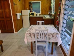 AmuriSunny Beach Bungalows - Aitutaki的厨房配有桌子、两把椅子和冰箱