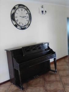 哈博罗内Sugar Shack Backpackers Botswana的钢琴上方墙上的钟