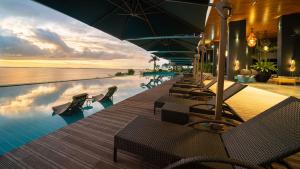 麦克坦The Reef Island Resort Mactan, Cebu的度假村的游泳池,配有椅子和遮阳伞