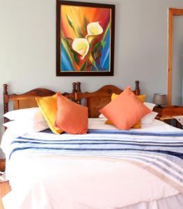 Ladybrand佳屋住宿加早餐酒店的一张带橙色枕头的床和墙上的绘画