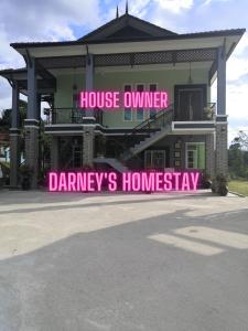 淡马鲁Darney's Homestay Kg Bangau Tanjung的前面有粉红色标志的大房子